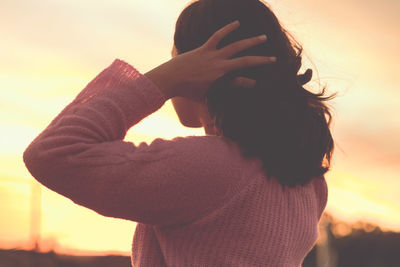 Portrait of woman standing against orange sky