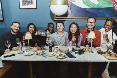 Portrait of smiling multiracial friends with wineglasses at restaurant