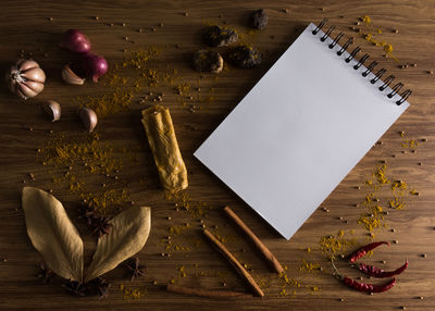 Directly above shot of spiral notebook with spices on table