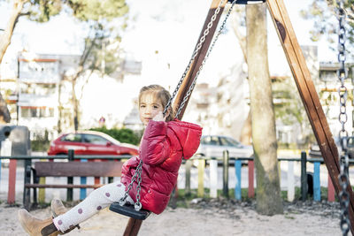 Portrait of girl sitting on swing at park