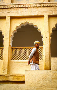 Side view of woman standing against building