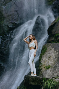 Rear view of woman standing against waterfall