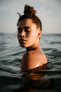 Side view of woman in sea against sky during sunset