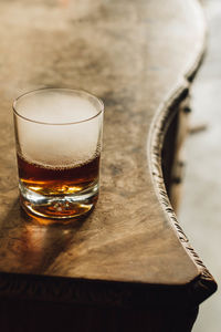Hazy whiskey in rocks glass with dry ice on wood credenza