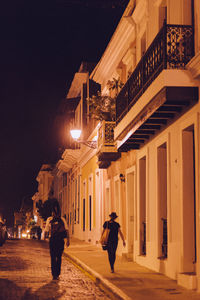 Woman walking on illuminated city street at night