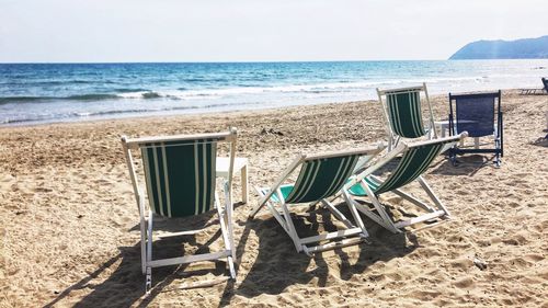 Empty deck chairs at beach during summer