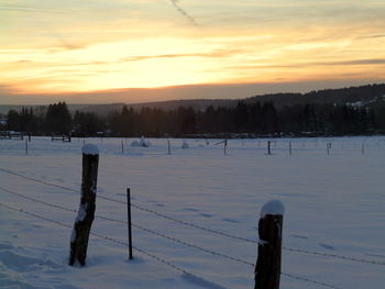 Scenic view of frozen field against sky during sunset