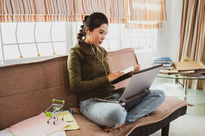 Woman using phone while sitting on sofa