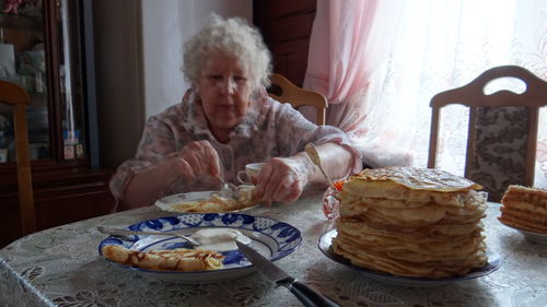 Portrait of man eating food on table at home