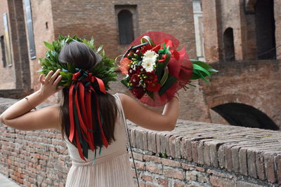 Rear view of graduated woman standing by building