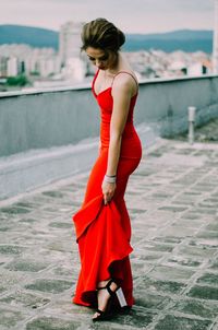 Woman in red dress standing on footpath