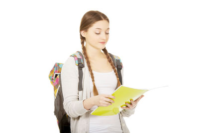 Young woman looking away while standing against white background