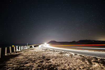 Light trails on road against sky at night