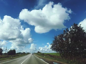 Empty road along landscape and trees against sky