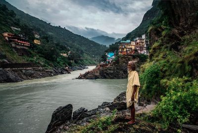 Man standing on rock by mountain against sky