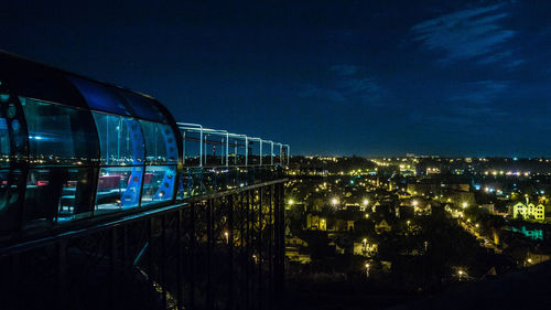 Illuminated cityscape against blue sky at night