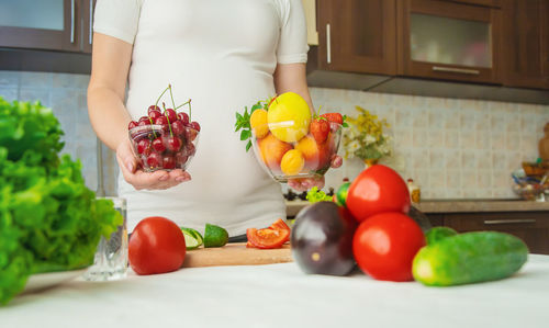 Midsection of woman picking tomatoes on table