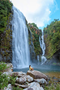 Rear view of man standing against waterfall