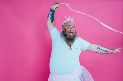 Portrait of man dancing against pink background