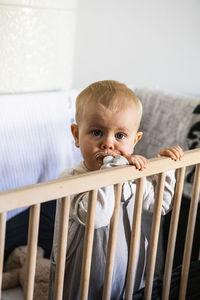 Baby boy in cot looking at camera