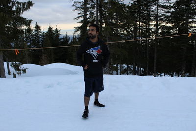 Full length of man standing on snow against trees