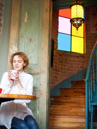 Full length of woman sitting on window