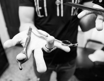 Midsection of barber holding equipment at shop