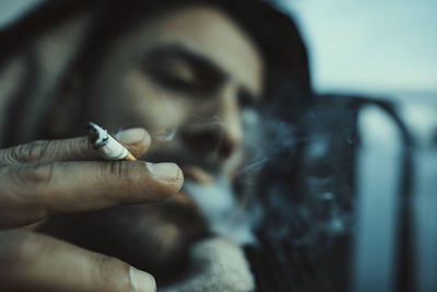 Close-up of young man smoking and  looking away