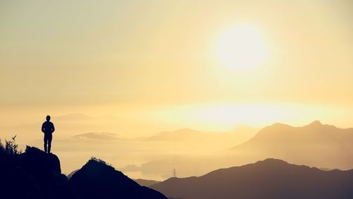 Man standing on cliff looking at mountains view