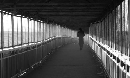 Rear view of man walking on footbridge
