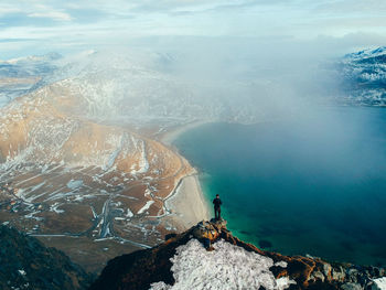 High angle view of man standing on mountain by sea