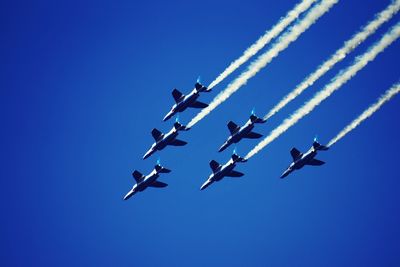 Low angle view of airshow against clear blue sky