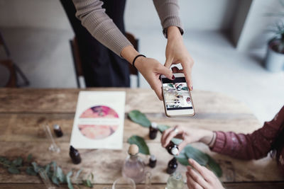 Midsection of woman holding smart phone on table