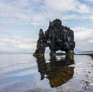 Rock formation on sea shore against sky