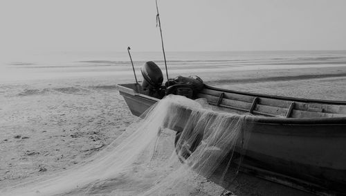 Boat moored on beach against sky