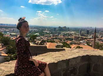 Woman looking at city buildings against sky