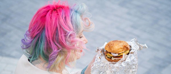 Caucasian woman with curly colored hair eating burger. bad eating habits and love of fast food