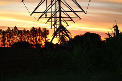 Silhouette trees on field against sky at sunset