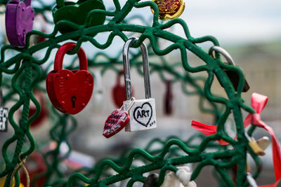 Close-up of heart shape padlocks hanging on metal against sky