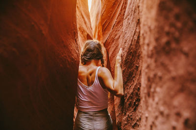 Rear view of woman standing on rock against wall