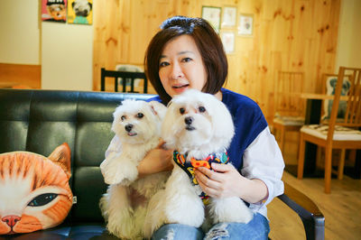 Portrait of woman with dog sitting at home