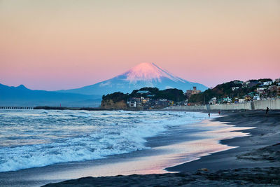 Scenic view of sea and snowcapped mountain against sky during sunrise