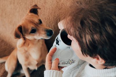 Woman having coffee with dog at home