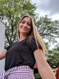 Portrait of smiling woman standing against trees