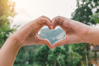 Close-up of hand holding heart shape against blurred background