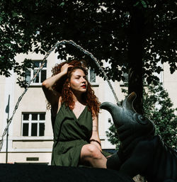 Happy young woman sitting on the fountain