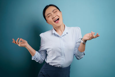 Young woman standing against blue background