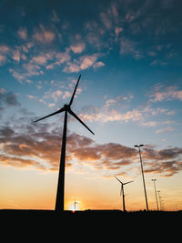 Silhouette windmills against sky during sunset