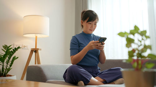 Young woman using phone while sitting at home