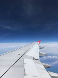 Cropped image of airplane flying against blue sky